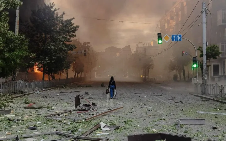 Woman walking past war-damaged buildings on smoky Kyiv street after Russian strikes