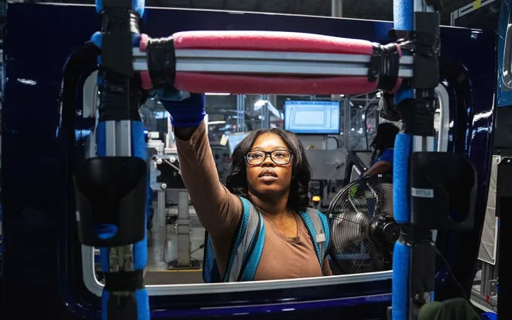Worker checking convertible-top windows on assembly line at Michigan auto plant