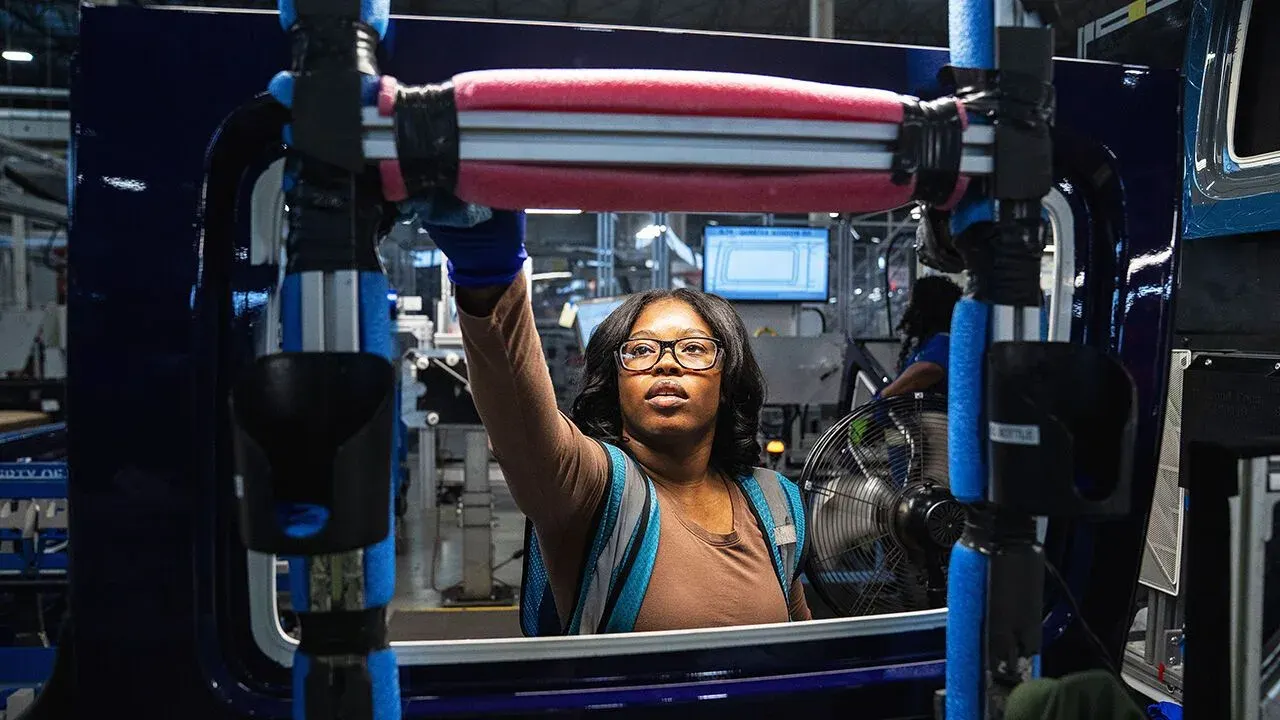 Worker checking convertible-top windows on assembly line at Michigan auto plant