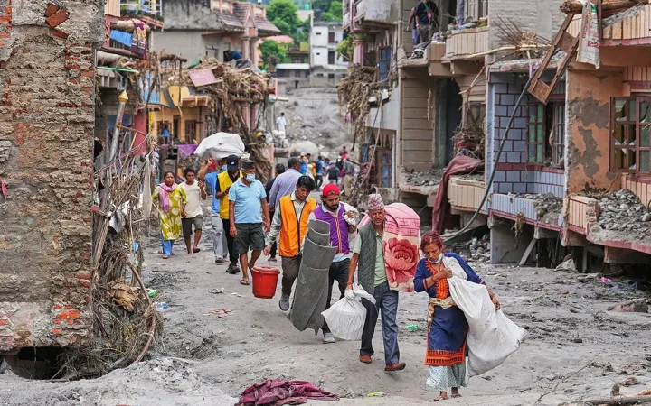 Survivors haul salvaged possessions through mud-filled ruined houses in Devighat, Nuwakot after Nepal floods