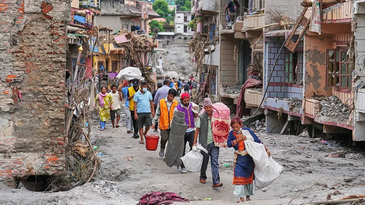 Survivors haul salvaged possessions through mud-filled ruined houses in Devighat, Nuwakot after Nepal floods