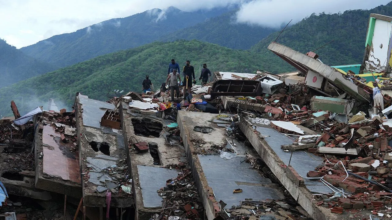 Residents search through rubble of a collapsed building after the June 24 earthquakes in La Guaira, Venezuela