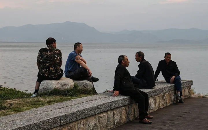 A group of men relax on the banks of Erhai Lake in Dali, Yunnan Province, China