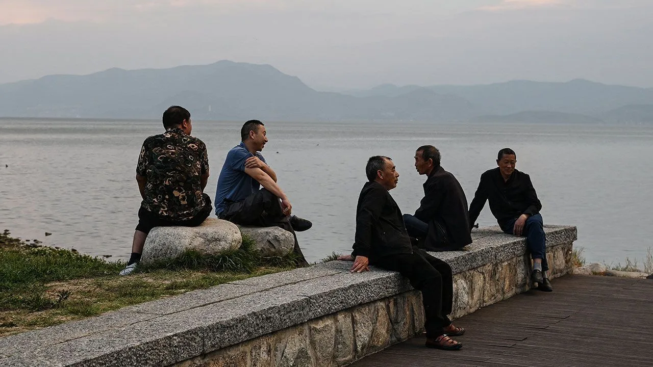 Men relax on the banks of Erhai Lake in Dali, Yunnan Province, China