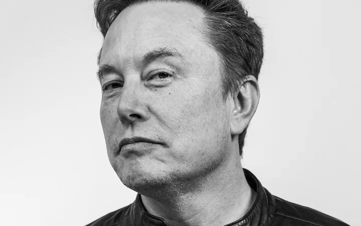 Black-and-white portrait of Elon Musk, wearing a leather jacket, looking to one side.