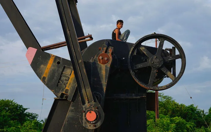 A boy sits on an inactive oil pumpjack in Cabimas, Venezuela.