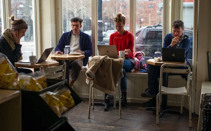 Patrons at a cafe use their laptop computers.