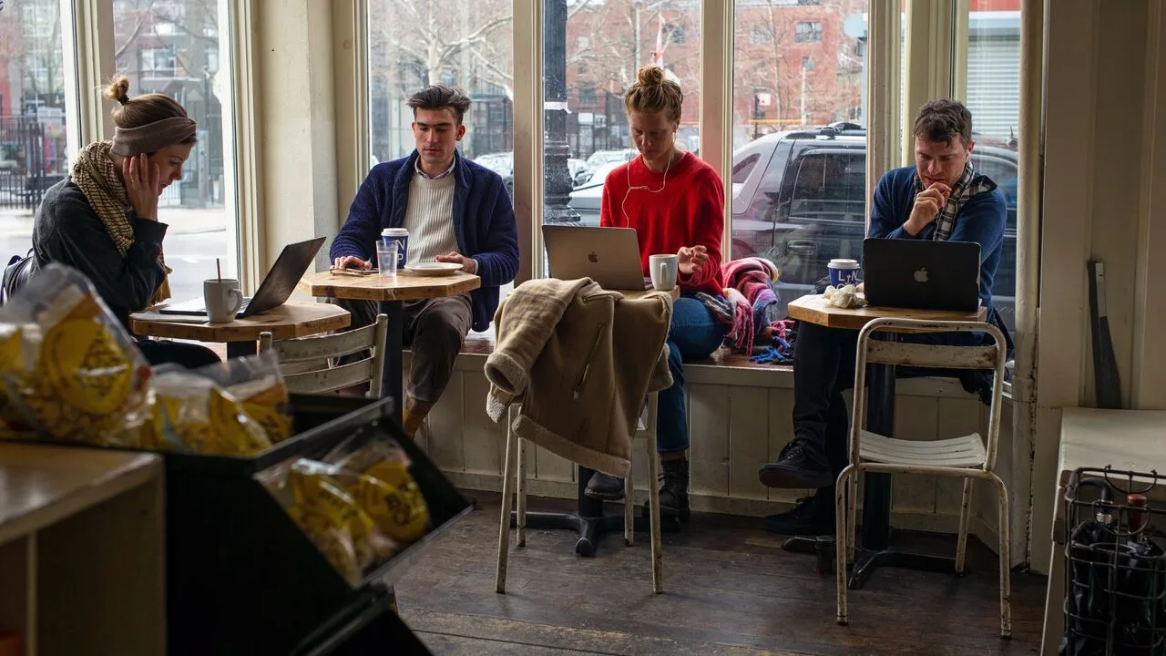 Patrons at a cafe use their laptop computers