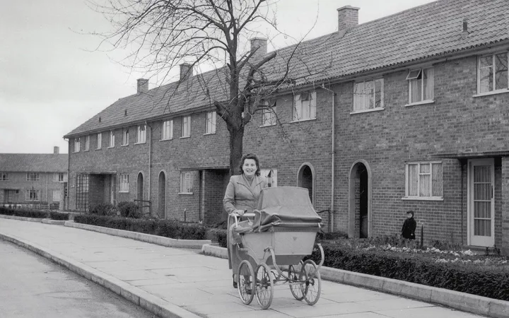 A woman pushes a pram past a row of council houses in the Adeyfield district of Hemel Hempstead, Hertfordshire.