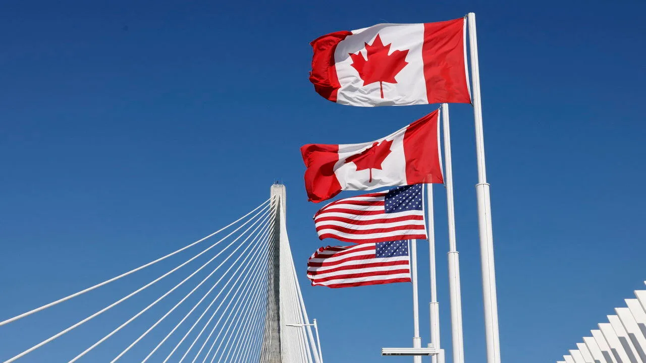 Flags of Canada and the United States fly across the international border on the Gordie Howe International Bridge connecting Windsor, Ontario, and Detroit, Michigan.