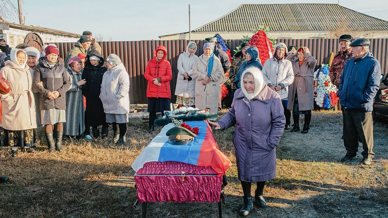 A group gathers outdoors around a decorated table at a rural community celebration.