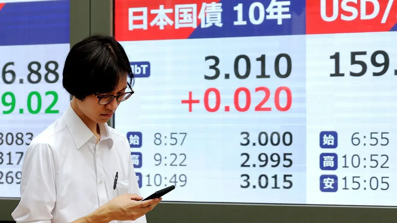 A passerby walks past a screen showing the yield on the 10-year Japanese government bond in Tokyo, Japan