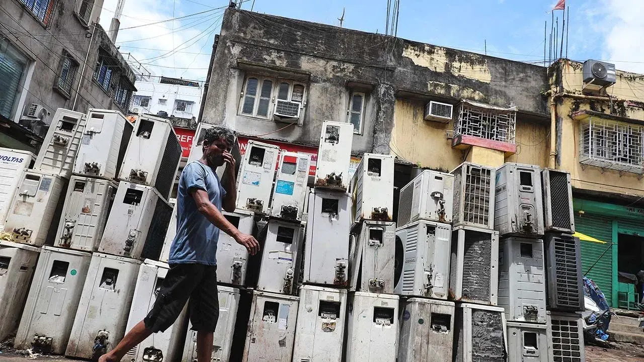 A worker walks past air conditioning units in Kolkata, India