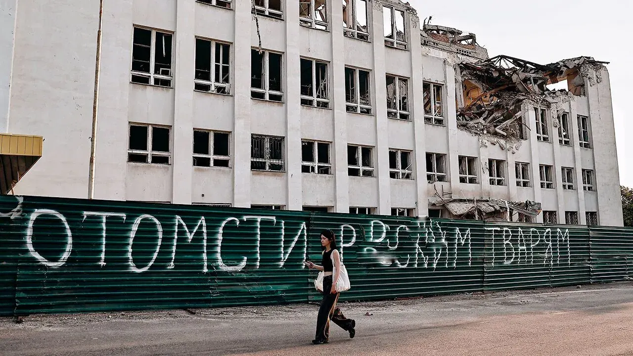 A woman walks past a building partially destroyed by Russian shelling in Kramatorsk, Ukraine