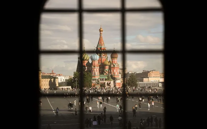 Visitors strolling in sunshine across Red Square by the Kremlin in Moscow