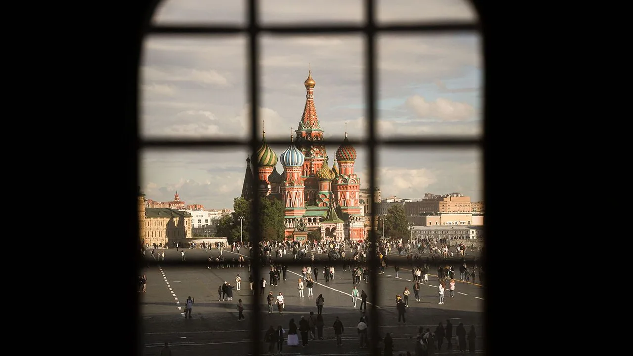Visitors strolling in sunshine across Red Square by the Kremlin in Moscow