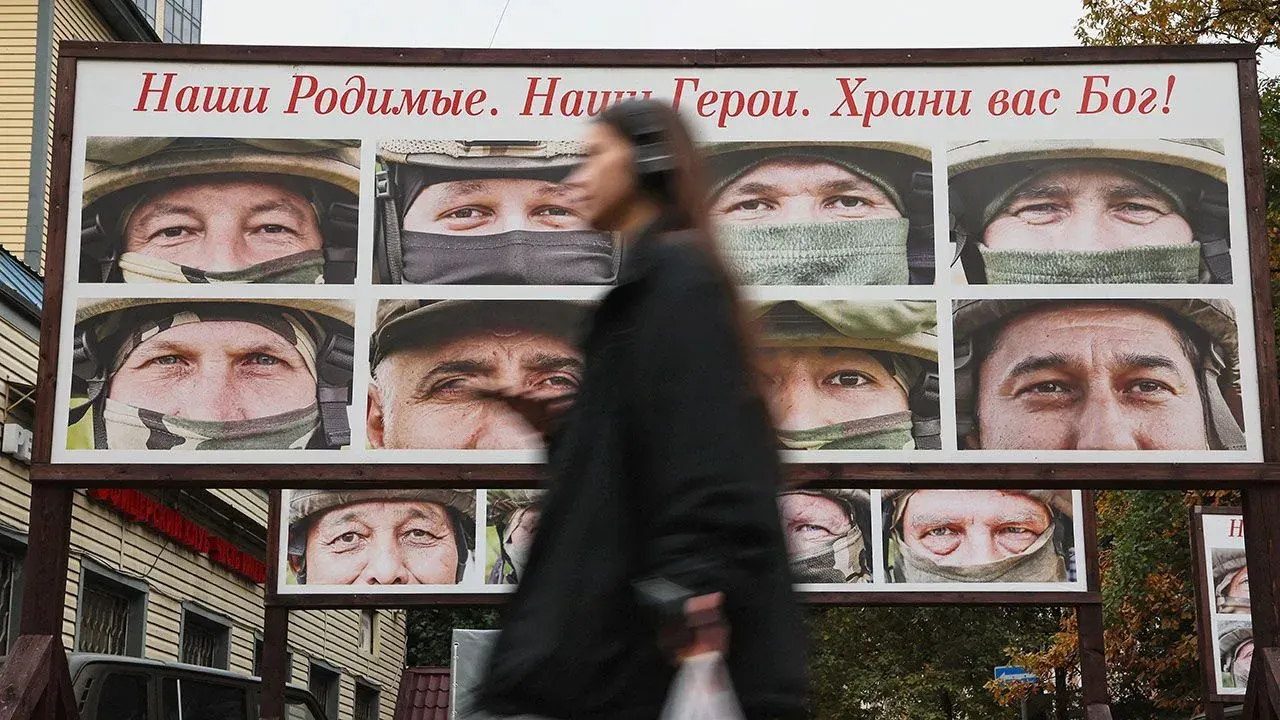 Pedestrian passing a display of portraits honouring Russian troops in the Ukraine campaign in Saint Petersburg