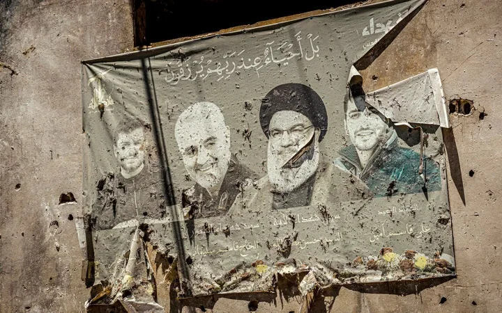 Bullet-riddled wall mural depicting Iranian leaders, including Ayatollah Khamenei, in a war-damaged building.