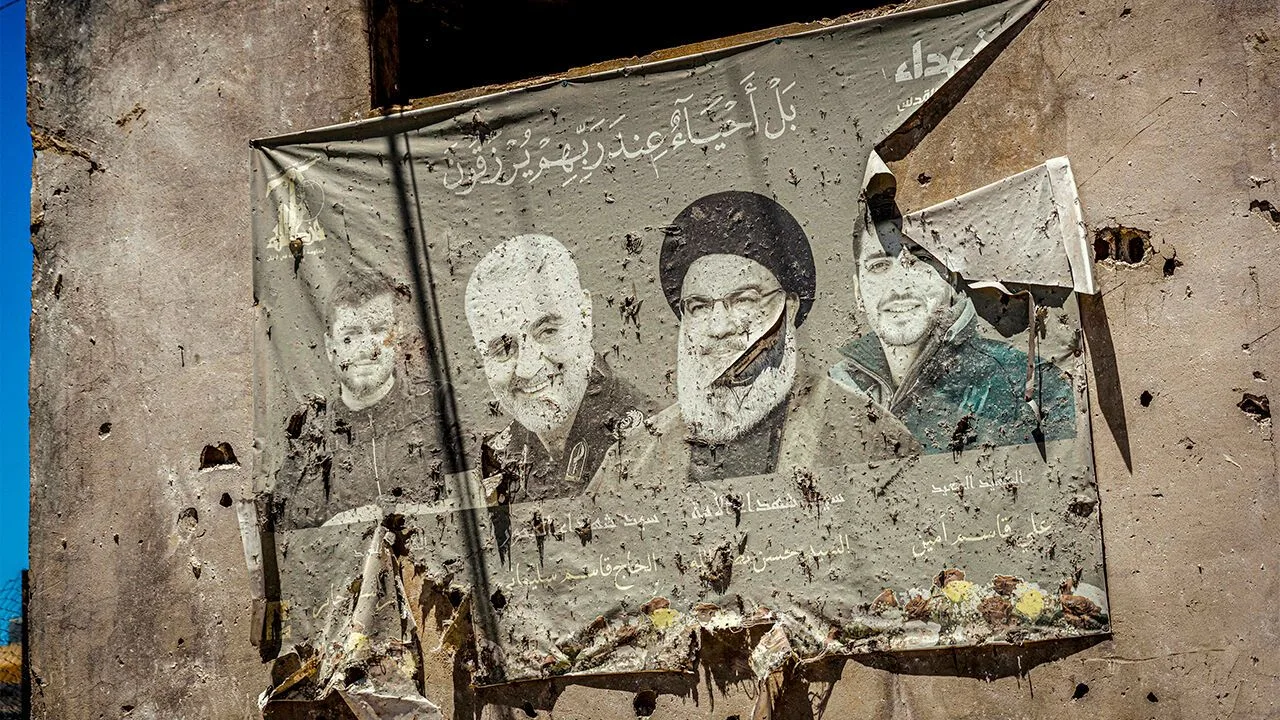 Bullet-riddled wall mural depicting Iranian leaders, including Ayatollah Khamenei, in a war-damaged building