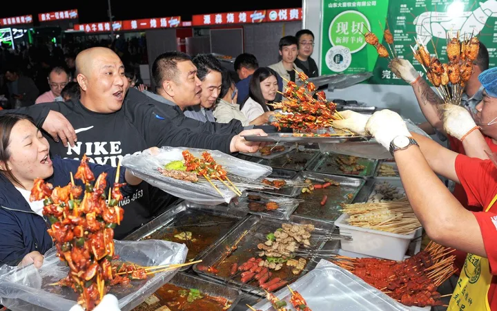 Tourists enjoy a barbecue feast at a gourmet marketplace during the five-day May Day Holiday on April 29, 2023 in Zibo, Shandong Province of China.