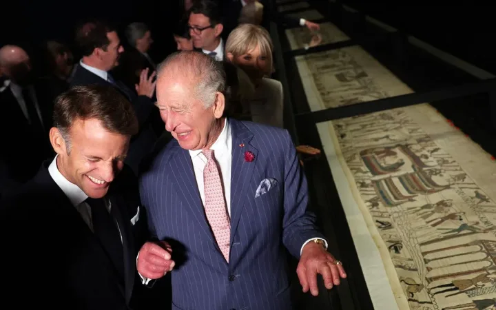 King Charles and President Emmanuel Macron examining portions of the Bayeux Tapestry together.