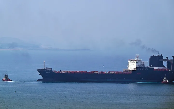 A tugboat guides a ship at the Khor Fakkan Container Terminal in the Gulf of Oman