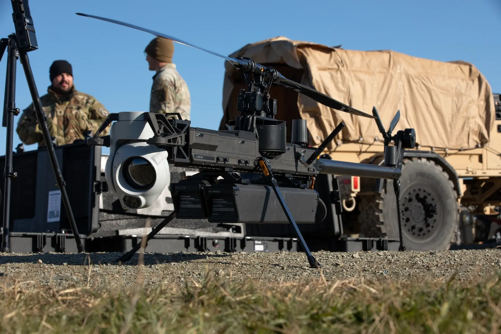 An Anduril Ghost-X drone on the ground with U.S. soldiers and a military vehicle behind it in Romania